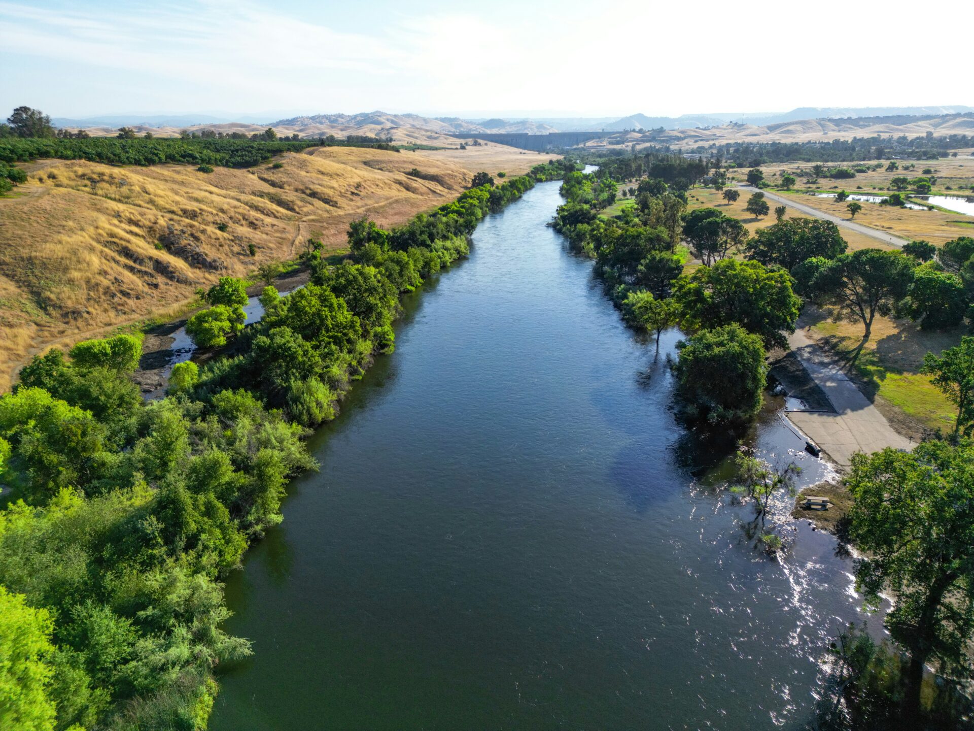 San Joaquin river with green and gold trees lining it.