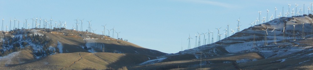 Renewable energy windmills on a golden grassy hill
