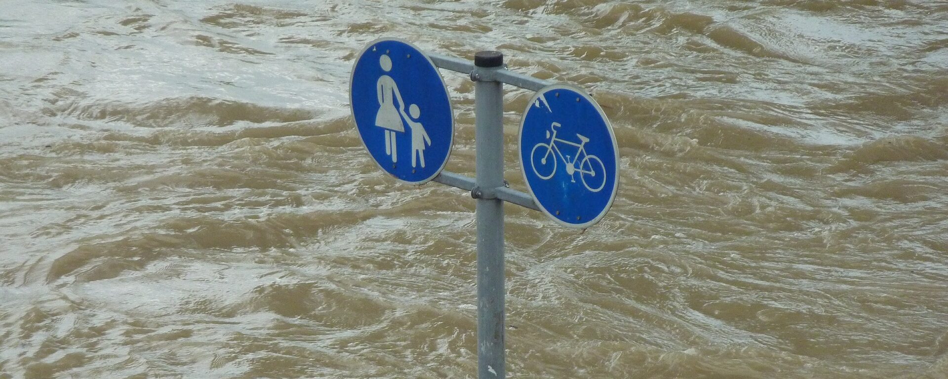 Street sign stick out of flood water.