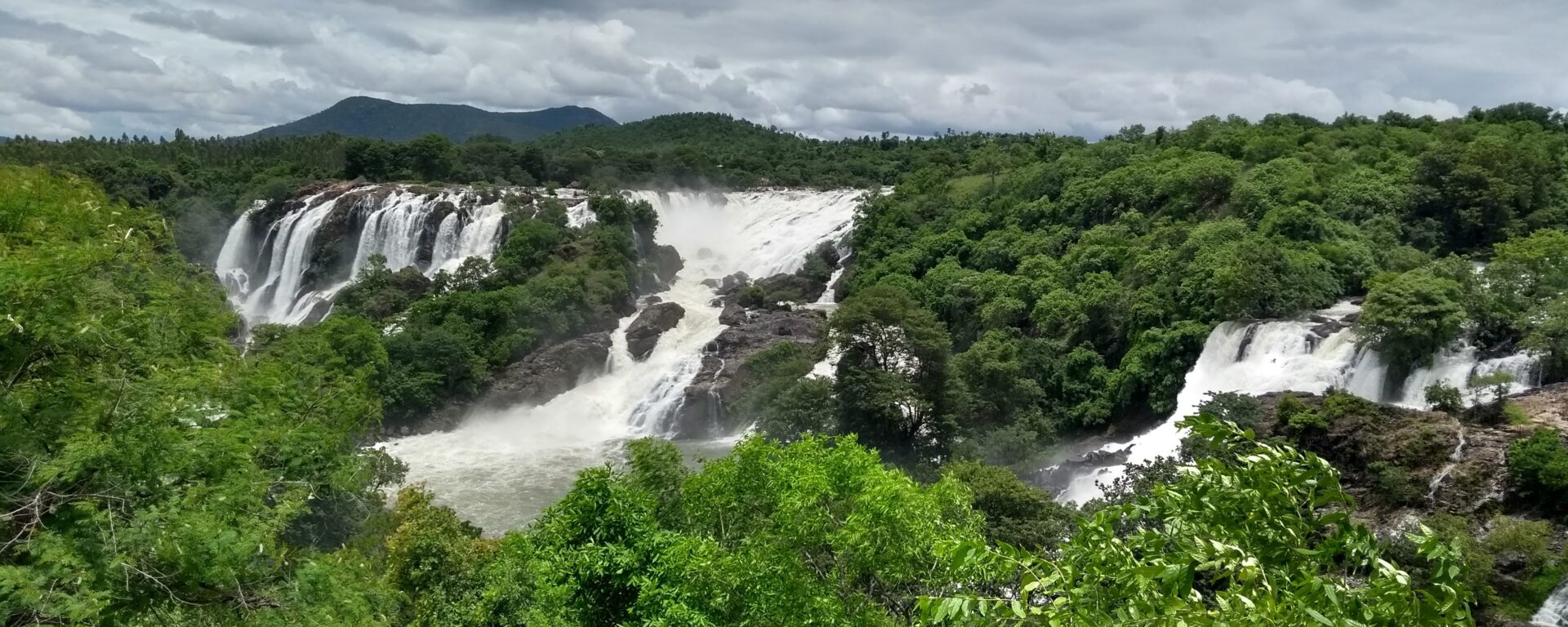 Lush greenery with multiple waterfalls from a large a rocky area