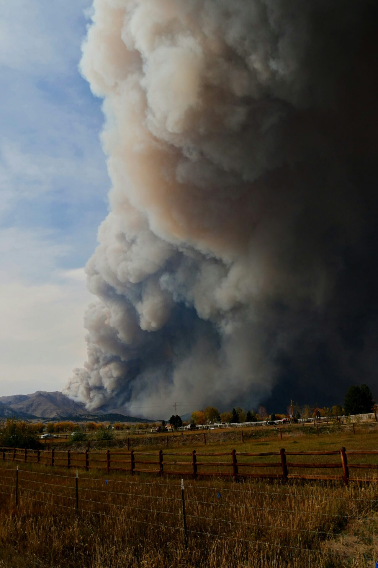 Grey and brown smoke rising from a dry grassy hill