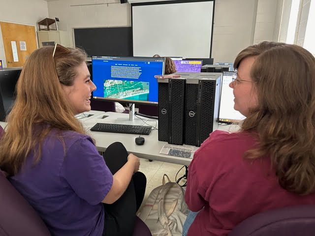Two female students in the classroom using data basin on their desktop computers