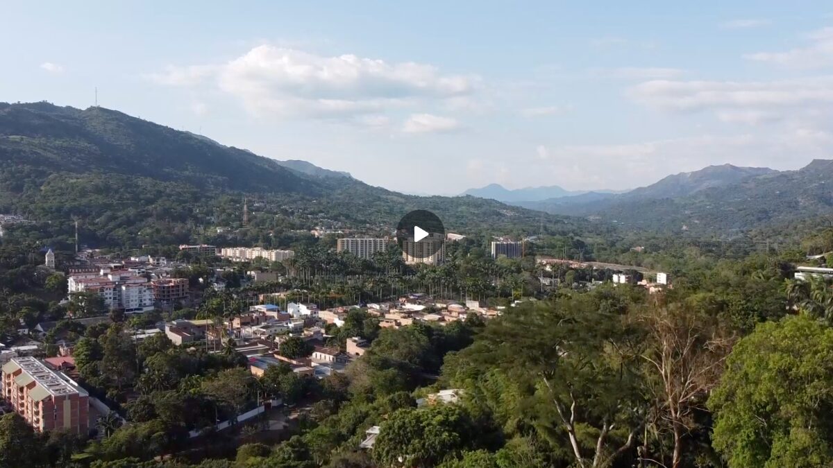 Image of an aerial view of a city Latin America with a play button in the middle of the image