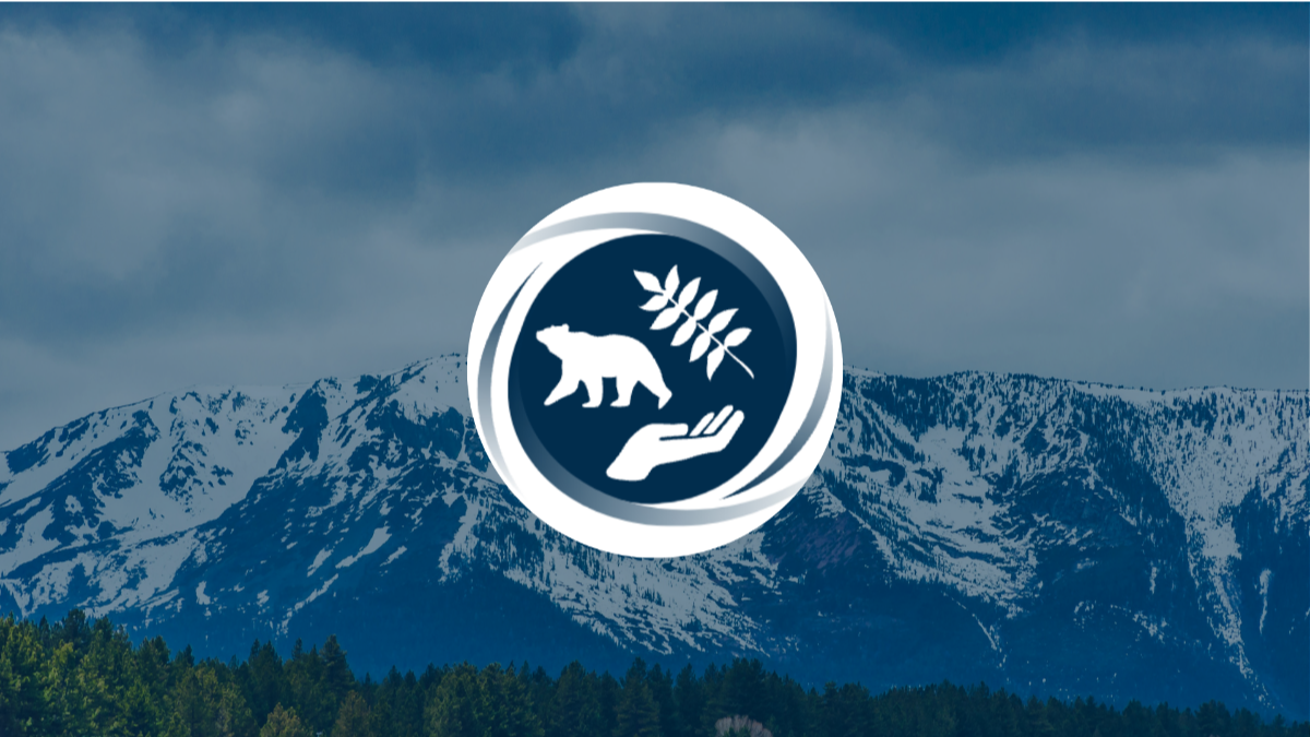 A logo featuring a bear, hand, and plant silhouette inside a circle is centered over a backdrop of snow-covered mountains under a cloudy sky